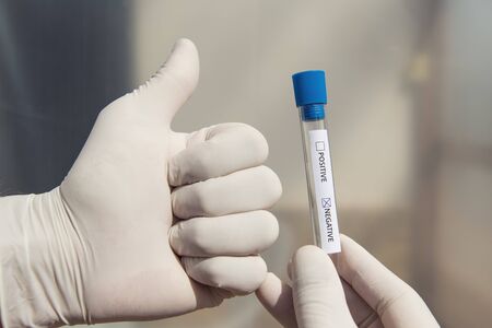 Soft focus hands of a lab technician with test tube. Negative result and hand shows ok.の写真素材