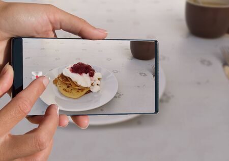 Woman photographing on cell phone homemade food.の写真素材