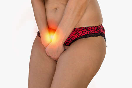 Closeup of woman with vaginal problems holding her crotch in bathroom.の写真素材