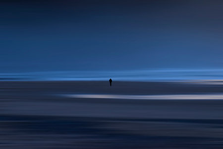A solitary figure walks pensively along Vega beach at dusk, in Asturiasの写真素材