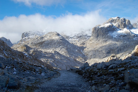 A rocky path between the snow-capped mountains of the Picos de Europa, in Cantabria, Spainの写真素材