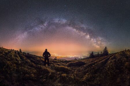 Person looks at the city and Milky Way glowing in the skyの写真素材