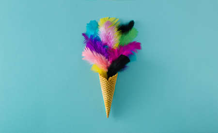 Colorful feathers in an ice cream cone layout with baby blue background. Minimal flat lay.の写真素材