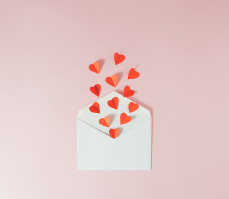Red paper hearts flying out of a white envelope - Valentine's love card. Minimal concept.