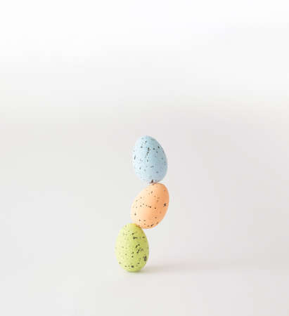 Three colorful styrofoam eggs stacked on white background.