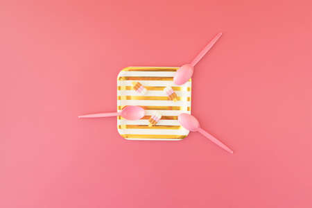 gold and white striped paper plate with three rubber ice creams and three pink plastic spoons on...