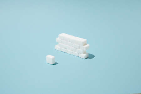 Wall made of sugar cubes as bricks with pink plastic spoon.