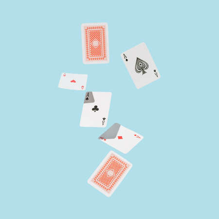 Playing cards falling against blue surface. Four aces. Minimal concept.