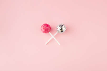 Lollipop candy and disco ball on lollipop stick on pink background. Flat lay. Top view. Minimal concept.の写真素材