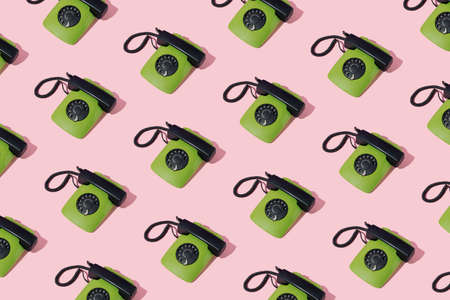 Retro 80s green rotary dial corded landline telephone pattern on pink background. Minimal concept.の写真素材