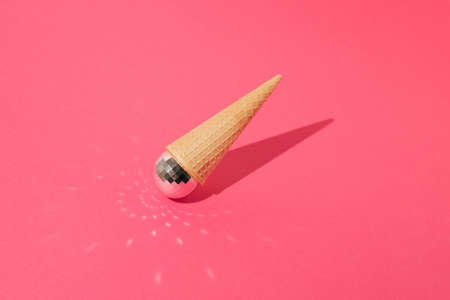 Ice cream cone with shiny disco ball turned upside down on pink background. Top view. Sharp shadow. Minimal concept.の写真素材