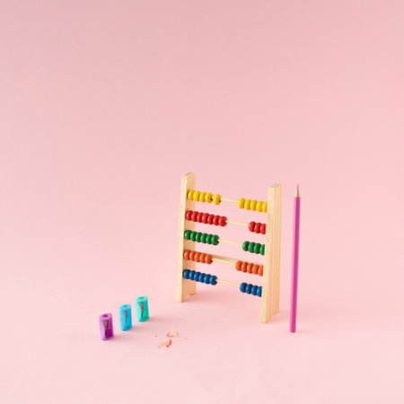 School abacus with colorful beads and pink crayon and sharpeners on pink background. Kids learning...