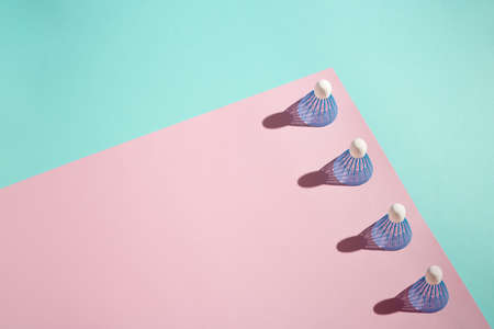 Badminton shuttlecocks (birdies) stacked on pink and blue background. Copy space.