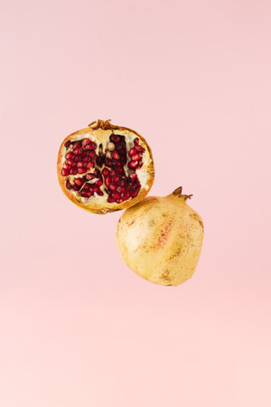 Fresh pomegranate cut in half levitating against pink background. Copy space. Front view.の写真素材