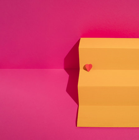 Yellow paper podium with red heart on magenta background. Minimal love or valentine concept.の写真素材