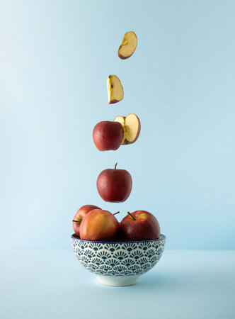 Ceramic bowl with fresh apples flying out of it. Minimal fruit concept.
