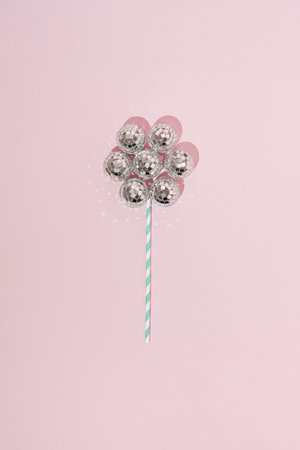 Shiny flower made with disco balls and paper straw. Minimal party concept. Flat lay. Top view.の写真素材
