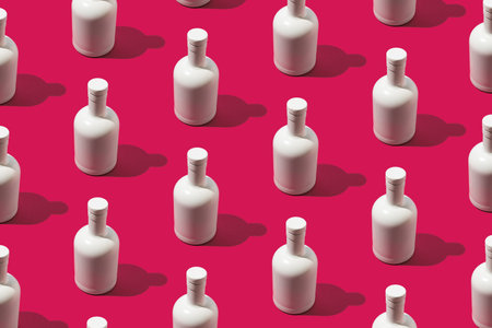Trendy beverage pattern made with white bottle on magenta background. Minimal vibrant concept.の写真素材