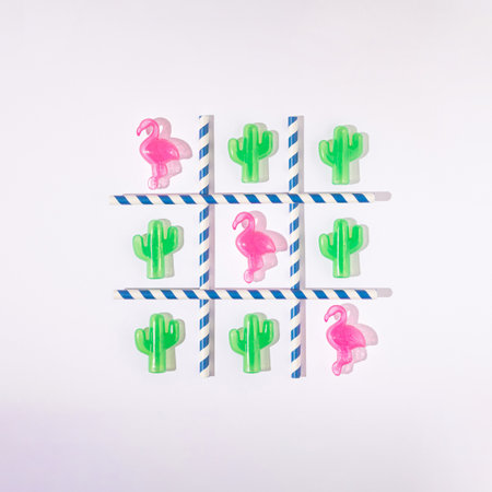 Tic tac toe made of pink flamingos, green catuses and straws. Flat lay. Minimal summer concept.の写真素材