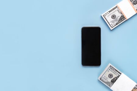 Mobile phone with a blank screen for inserting text, images and 50, 100 dollar bills on a blue backgroundの写真素材