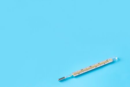 Glass thermometer for measuring body temperature on a blue background. Copy space. Empty space for inserting textの写真素材