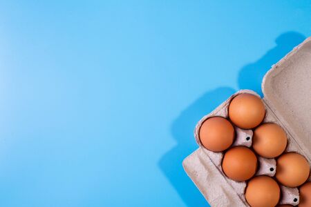 Raw chicken eggs in a package on a blue background. Copy space. Space for text. Top View
