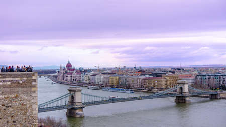 Budapest, Hungary 03 16 2019: Tourists look at the city from above the Buda Castle. In the background the parliament and the chain bridge. Image in shades of purple.のeditorial素材