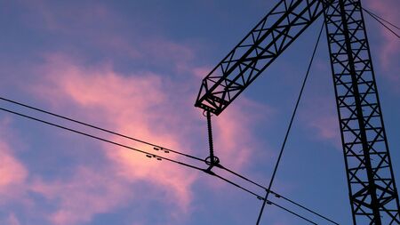 Silhouette of high voltage electric tower at beautiful sunset with dramatic cloudsの写真素材