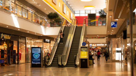 Gyor Hungary 05 21 2020: Young woman in mask using escalator in a shopping mall due to coronavirus.
