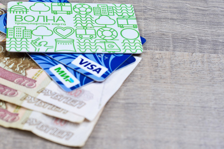 Plastic transport card and plastic cards of VISA and MIR payment systems on 100 roubles par value paper banknotes on brown background. Russia Volgograd region 14 March 2017のeditorial素材