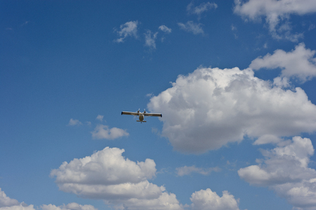 Light airplane against the blue sky with white clouds backgroundの写真素材