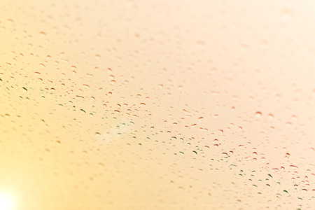 Water drops on glass against the sunset backgroundの写真素材