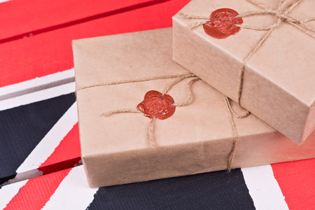 Boxes, wrapped into craft paper, fixed with packthread with a wafer on a background of a wooden candlestick on a coloured wooden desk.の写真素材
