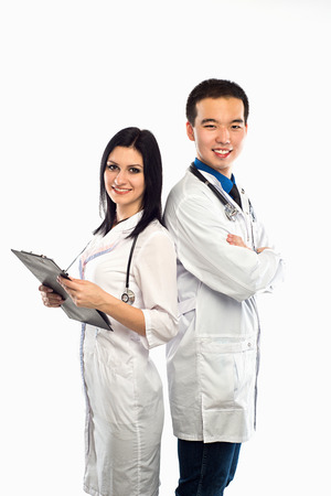Asian doctor with a smiling happy Caucasian nurse or medical colleague standing back to back with folded arms isolated on white, upper body portrait conceptual of healthcareの写真素材