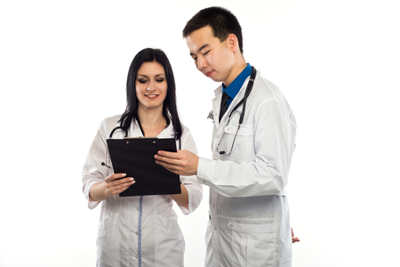 Medical multiethnic staff having discussion in a hospital hallway. Male and female nurse wearing blue scrubs working in a medical clinic. Two hospital workers discussing on laboratory test.の写真素材
