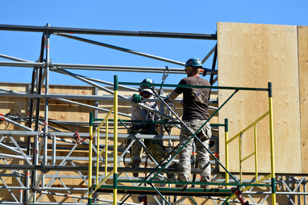 Pair of mounting work fixed plywood panels on top, working on specially constructed scaffolding.  Volgograd, Russia 27 may 2018のeditorial素材