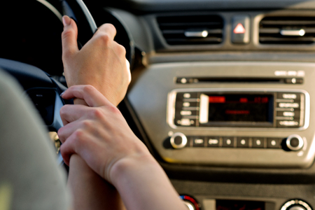 A couple of girls in the front seats of the car on the way to the sunset. She's driving, she's holding her hand. Shooting close-up about driving safety. Chase the sunset! Travelling sweetheartsの写真素材