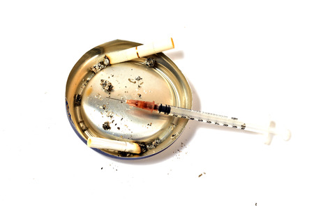 Syringe and several cigarette butts on an improvised ashtray (isolated on white)の写真素材