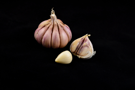 Onion and a pair of garlic cloves, lie on a black background, close-upの写真素材