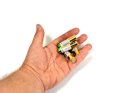 Several spent color alkaline batteries in the hand of a man on a white background. Recycling, energy, energy, environment and ecology concept-close your hands holding alkaline batteries pile. Russia, Volgograd, August 19, 2018のeditorial素材