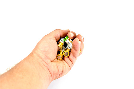 Several spent color alkaline batteries in the hand of a man on a white background. Recycling, energy, energy, environment and ecology concept-close your hands holding alkaline batteries pile. Russia, Volgograd, August 19, 2018のeditorial素材