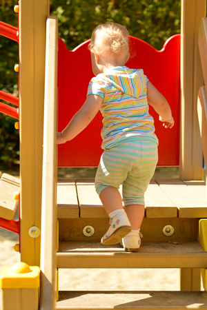 The girl is walking on the steps of the children's town on the Playground on a Sunny day.の写真素材