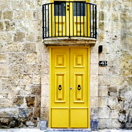 Old wooden doors painted yellow with antique cast iron handles. Entrance doors to the apartment in...
