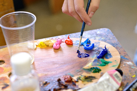 cropped image of left-handed artist taking paint from palette in workshopの写真素材