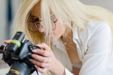 the Portrait blonde girl in glasses. She look at cameras screen and choose picturesの写真素材