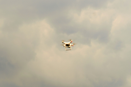 Hovering drone with camera in clear blue sky and cloud with copy space.