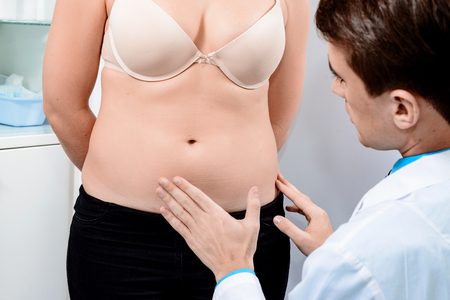 Practical consultation of the surgeon to remove excess fat in the abdomen. Examination of the patient before the liposuction procedure.の写真素材