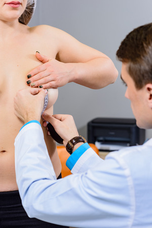 Hands of the doctor and the patient's chest, measuring the diameter (radius) of the breast in a calm state close-Upの写真素材