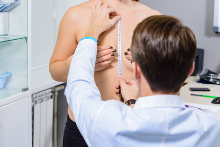 Examination of the plastic surgeon. The doctor's hands and the patient's chest, measuring the symmetry of the center of the breast in a calm state close-Upの写真素材