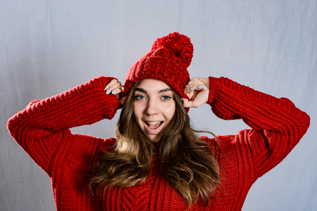 Fashionable young woman posing ,wearing red knitted sweater and red cap. Elegant woman wearing trendy outfit.Fashion portrait of beautiful young woman.の写真素材